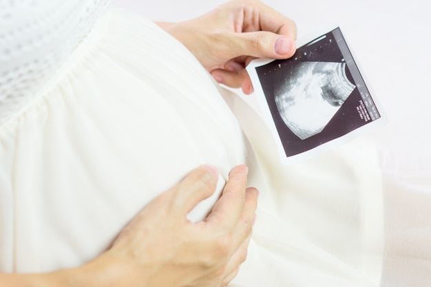 Mujer asiática embarazada que mira la exploración del ultrasonido