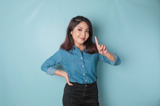 Mujer asiática emocionada con una camisa azul que da el número 12345 con un gesto manual