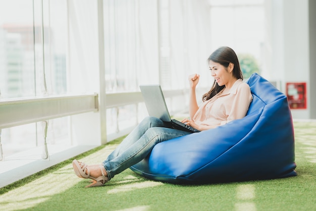 Mujer asiática emocionada que usa la computadora portátil