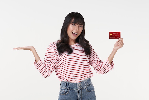 Mujer asiática emocionada sosteniendo una tarjeta de crédito simulada para dinero de transacción mirando la cámara