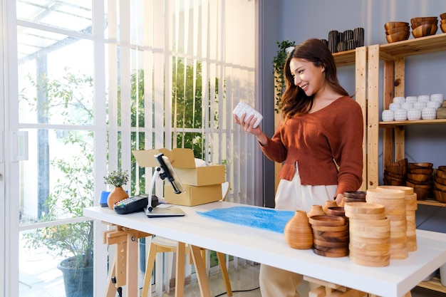 Mujer asiática empacando un jarrón con envoltura de burbujas de aire para un producto frágil antes de enviar el paquete