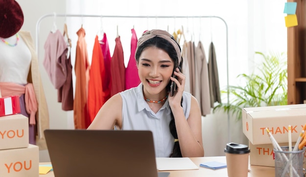 Mujer asiática empresaria que vende productos de pedidos de cheques de ropa que trabajan en pequeñas empresas de inicio en casa