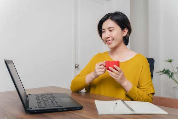 Mujer asiática empresaria tomando café para curar el concepto de somnolencia mujer asiática divirtiéndose tomando café durante el trabajo