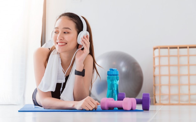 Mujeres asiáticas sanas escuchando música con auriculares mientras hacen  ejercicio en el gimnasio