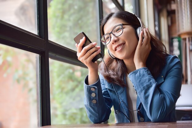 Mujer asiática escuchando la música con auriculares.