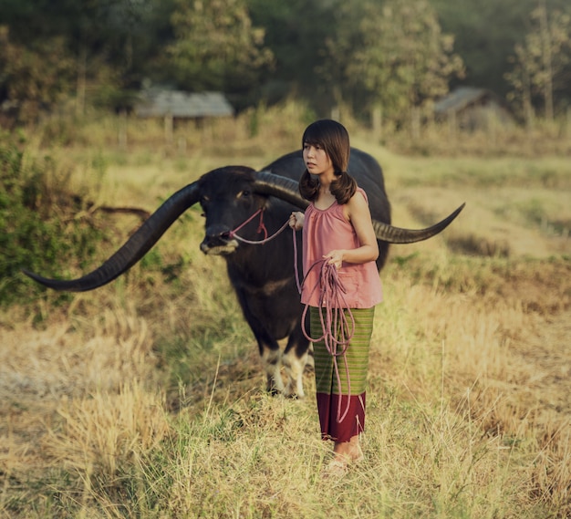 Mujer asiática escuchando radio con su búfalo, Tailandia