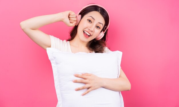 Mujer asiática está abrazando la almohada en rosa