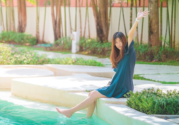 Mujer asiática se está relajando en un jardín y piscina de resort de verano