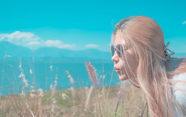 La mujer asiática está soplando la flor de la hierba en el viento en la naturaleza