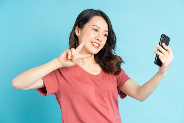 Mujer asiática está usando un teléfono inteligente para tomar selfies