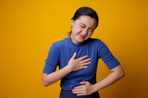 La mujer asiática estaba enferma con dolor de estómago tomados de la mano presionando su abdomen.