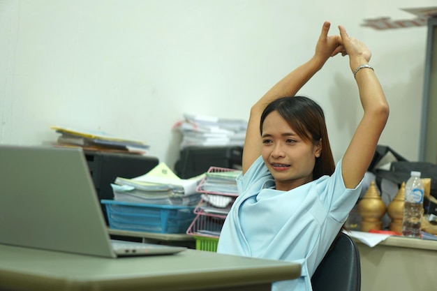 Mujer asiática estirando los brazos debido a una larga sesión