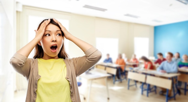 mujer asiática estresada sosteniendo su cabeza en la escuela