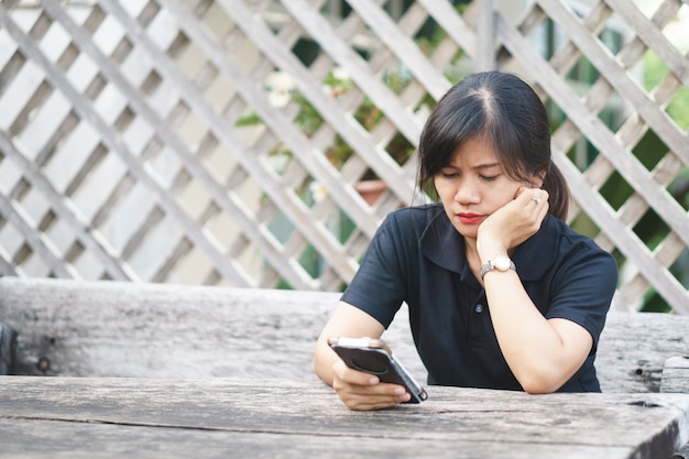 Una mujer asiática con expresión seria en el teléfono.