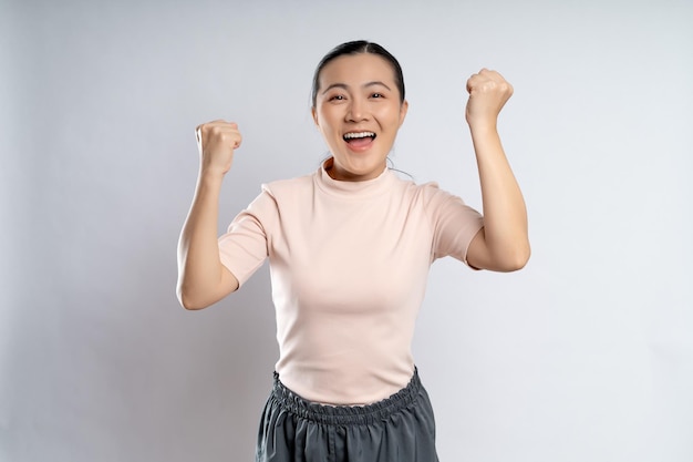 Foto mujer asiática feliz confiada mostrando su puño hacer un gesto ganador