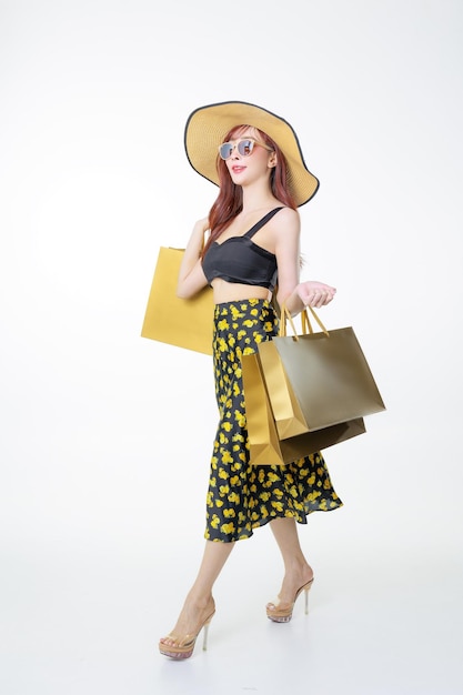 Mujer asiática feliz con cuerpo perfecto posando en el estudio Modelo femenino de moda de lujo en vestido sexy con bolsas de compras en fondo blanco aislado Ecommerce Concept de compras en línea