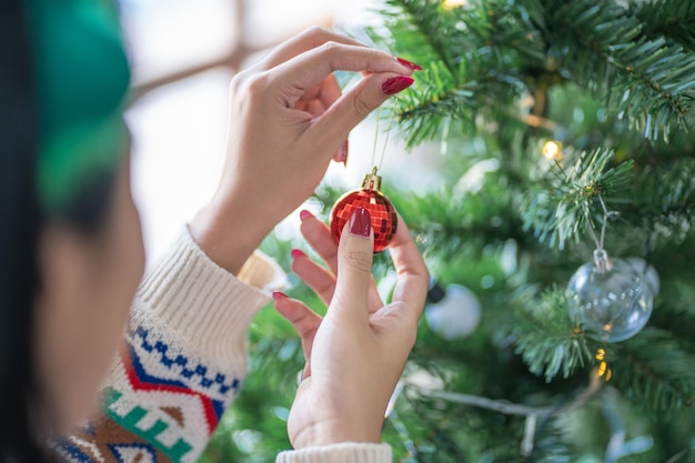 Mujer asiática feliz decorando el árbol de Navidad para las vacaciones de Navidad
