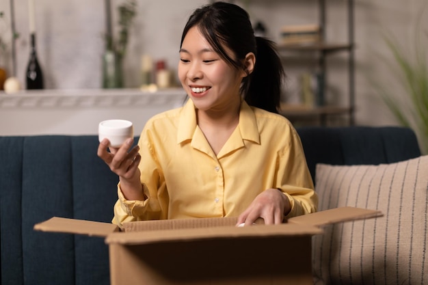 Mujer asiática feliz desempacando el paquete después de comprar en línea