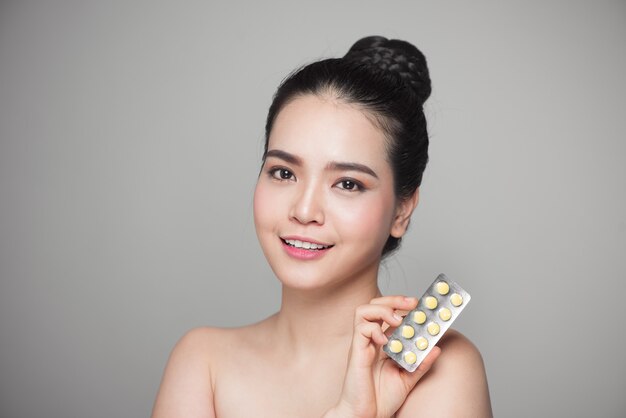 Mujer asiática feliz sana con pastillas en la mano.