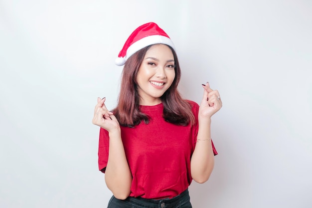 La mujer asiática feliz de Santa sonríe y da formas románticas. El gesto del corazón expresa sentimientos tiernos aislados por el concepto de Navidad de fondo blanco.