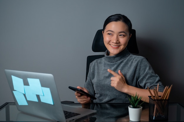 Mujer asiática feliz sonriendo mirando copia espacio, trabajando en una computadora portátil en la oficina