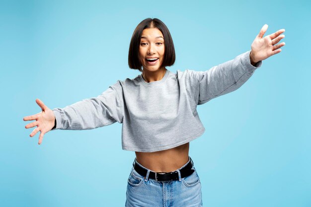 Mujer asiática feliz y sonriente con un traje casual elegante mirando a la cámara abrazándose de pie aislada sobre un fondo azul concepto de estilo de vida positivo