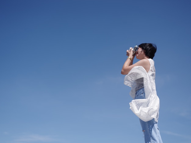 Mujer asiática feliz y sonrisa en la playa y el cielo azul