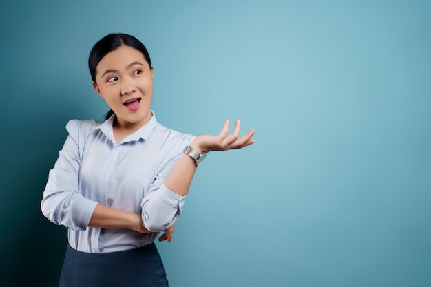 Mujer asiática feliz sorprendida posando en azul.