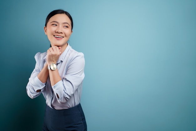 Mujer asiática feliz sorprendida posando en azul.