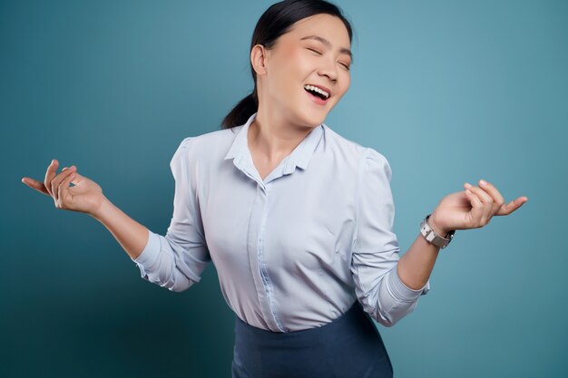 Mujer asiática feliz sorprendida posando en azul.