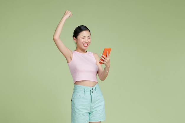 Mujer asiática feliz sosteniendo un teléfono inteligente y ganando el premio