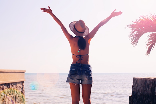 Foto mujer asiática feliz en top bikini y pantalones cortos en la playa. concepto de verano