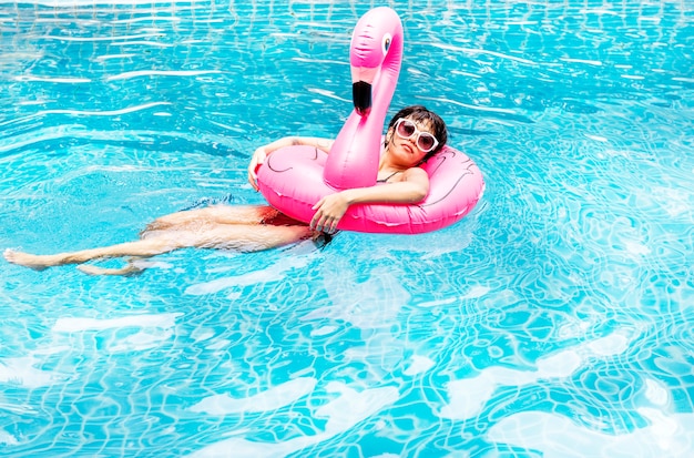 Una mujer asiática flotando en la piscina con flotadores inflables