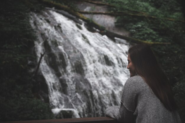 Foto mujer asiática en fondo de bosque y agua caída