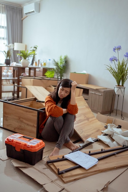 Mujer asiática frustrada mientras ensambla muebles nuevos