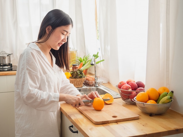 Mujer asiática con fruta en la cocina.