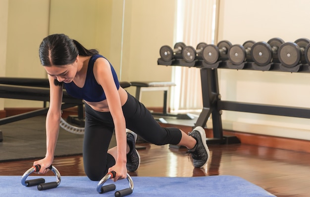 La mujer asiática fuerte está haciendo un tablón en un gimnasio de la aptitud