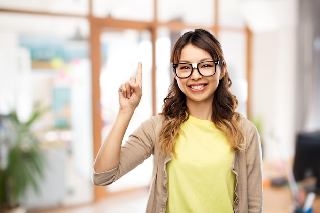Foto mujer asiática con gafas con el dedo en la oficina