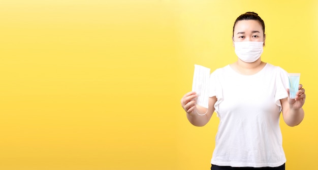 Mujer asiática con gel de alcohol y máscara médica, recomienda la prevención de virus y diversas enfermedades. aislado sobre fondo amarillo en estudio con copia espacio.