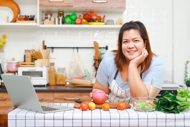 Mujer asiática gorda que disfruta cocinando en la cocina Aprenda a hacer ensaladas y comidas saludables de las redes sociales Concepto de atención médica Coma alimentos saludables para perder peso