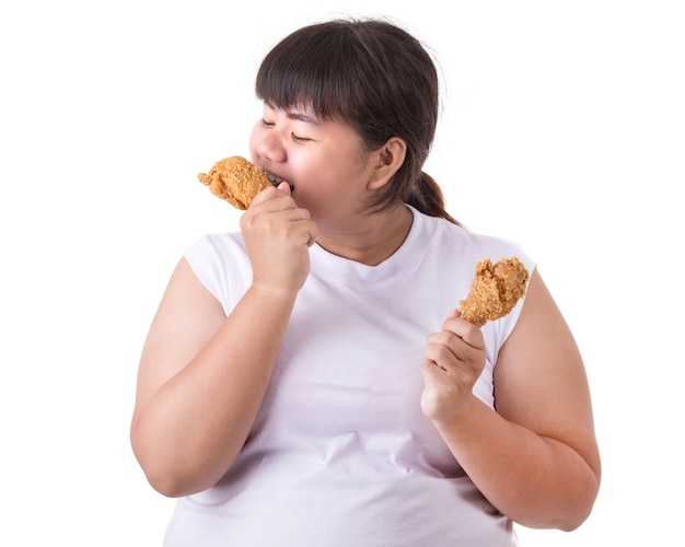 Mujer asiática gorda que sostiene y que come el pollo frito