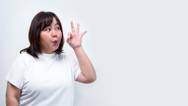 Foto mujer asiática gordita mostrar diferentes gestos con expresiones faciales y señalar con la mano representa un símbolo de comunicación en un fondo blanco para el espacio de copia