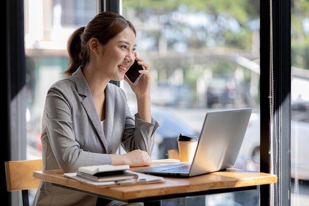 Mujer asiática hablando por teléfono, es vendedora en una empresa nueva, llama a los clientes para vender productos y promociones Concepto de venta de productos a través de canales telefónicos