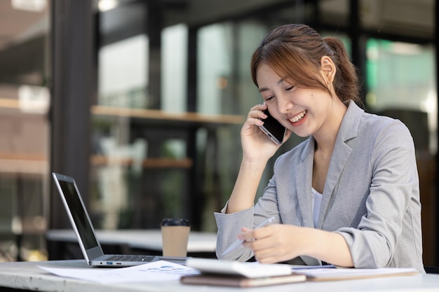 Mujer asiática hablando por teléfono, es vendedora en una empresa nueva, llama a los clientes para vender productos y promociones Concepto de venta de productos a través de canales telefónicos