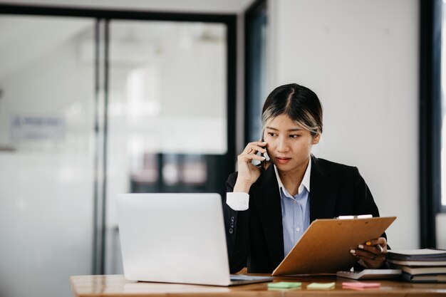 Mujer asiática hablando por teléfono, es vendedora en una empresa nueva, llama a los clientes para vender productos y promociones Concepto de venta de productos a través de canales telefónicos