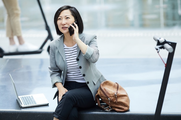 Mujer asiática hablando por teléfono inteligente en la ciudad