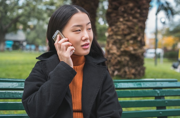 Mujer asiática hablando por teléfono.