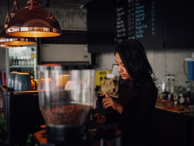 Mujer asiática haciendo café con máquina de café en café