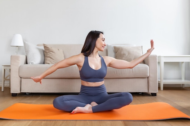 Mujer asiática haciendo ejercicio en casa estirándose Tiempo para yoga Mujer joven atractiva y saludable haciendo ejercicios mientras descansa en casa Mujer joven haciendo ejercicio en el interior de su casa