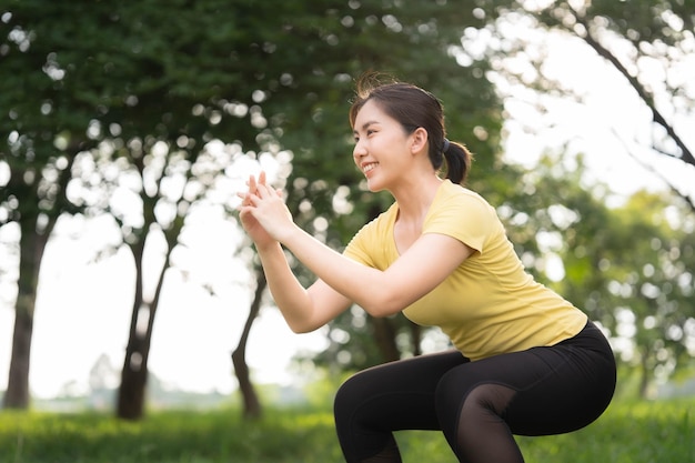 Mujer asiática haciendo ejercicio en cuclillas en el parque fitness y concepto de atención médica